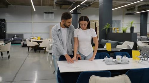 Just Married Couple Choosing Dining Table in Furniture Store