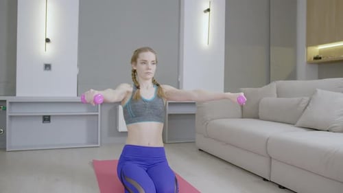 Woman Doing Shoulder Exercise with Dumbbells Indoors