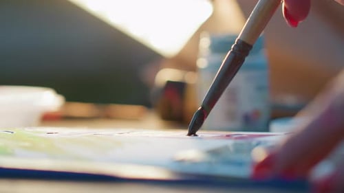 Close Up Artist Hand Painting Colorful Strokes on Paper Under Glowing Lamp