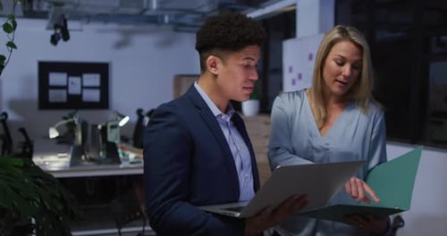Biracial man and Caucasian woman review business documents in an office