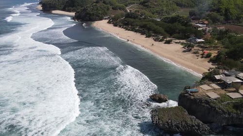Drohnenaufnahme von Sonnenschirmen, Booten und Menschen, die am Strand in Yogyakarta, Indonesien, Urlaub machen