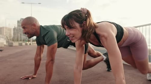 Close-up side view of happy multi-ethnic couple training outdoors, doing crossfit outside