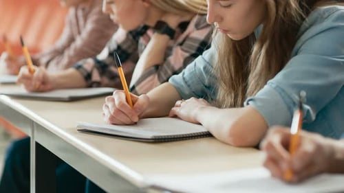 Moving Footage of a Row of Multi Ethnic Students in the Classroom Taking Exam/ Test. Focus on Holdi