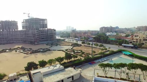 Aerial tilting down view of a highway of the city with traffic going on, under constructed building