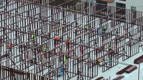 Baustelle mit Bauarbeitern, die Metallrahmenwände zusammenbauen, Luftaufnahme einer großen Bebauung