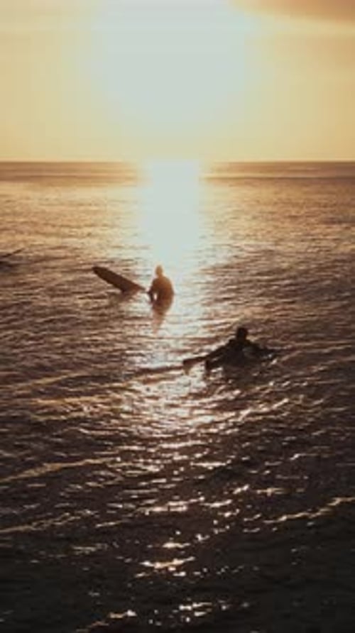 Sunset Silhouettes Of Paddleboarders And Surfers Amid Peaceful Ocean Glow