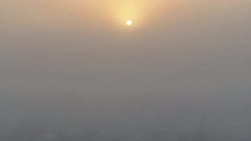 Golden sunrise drone view as it flies up out of the morning fog.