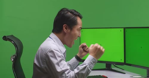 Happy Asian Man Celebrating And Dancing While Working With Mock Up Multiple Monitor In Green Screen