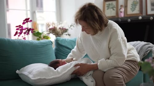 Senior Woman Soothing a Newborn Baby on Couch