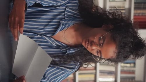 Young Admiring Indian Woman Unfolds Received Letter Sits at Table in Library