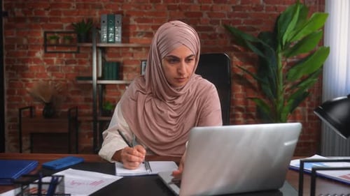 Focused Businesswoman in Hijab Working on Laptop in Office
