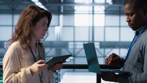 Team of Technicians Working in Server Farm Using Laptops to Analyze Data