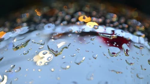 Close up of raindrops on a bauble with colorful lights