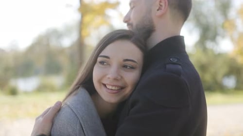 Man and a Smiling Woman are Hugging Each Other in a Park