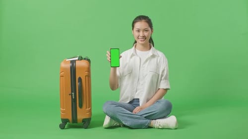 Full Body Of Female Traveler With Luggage Showing Green Screen Smartphone In The Green Screen