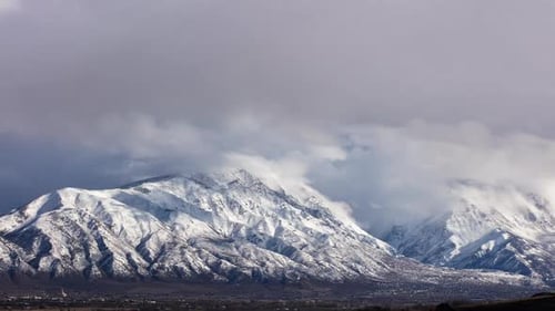 Timelapse of clouds moving over snow capped mountains
