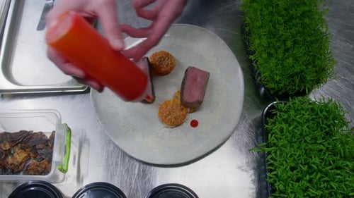 Chef Plates Steak with Orange Sauce in Kitchen