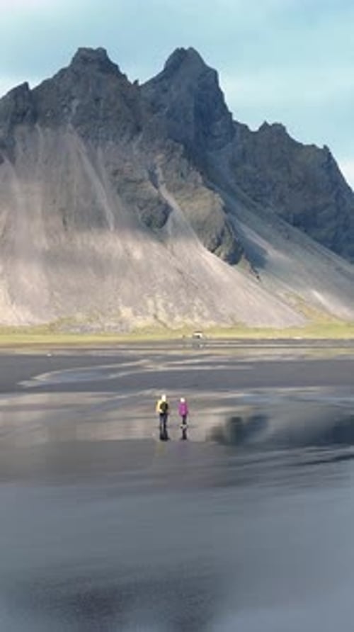 Exploring the Black Sand Beach in East Iceland Under Majestic Mountain Peaks
