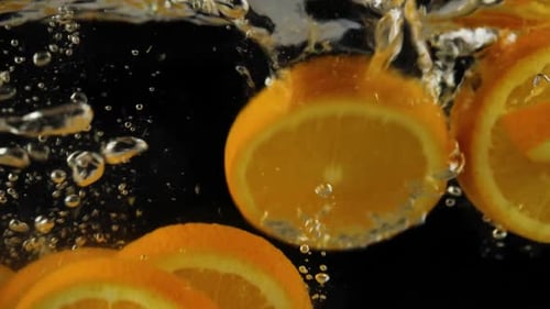 Bright Orange Slices Falling Into Water