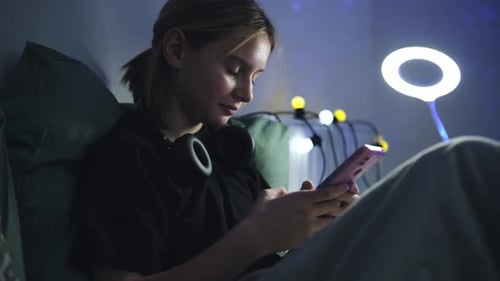 Teenage Girl Using Smartphone in Bedroom at Night