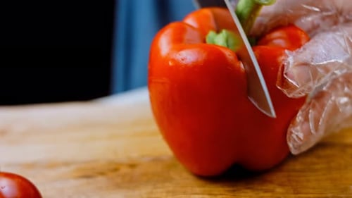 Front View of the Young Chef Cut Thin Slices of a Piece of Red Pepper with a Knife on the Cutting