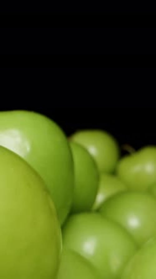 Vertical video. Macro Dolly, Pile of Green Plums on Black Background.