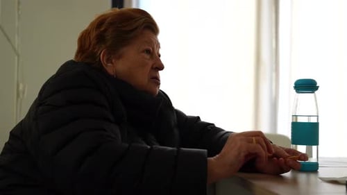 Granny at the table eating several small salty crackers