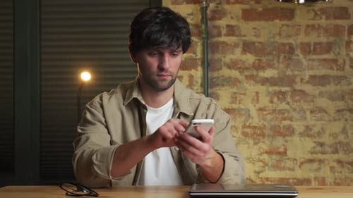 Young Adult Using Smartphone at Table Indoors