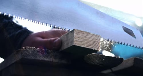 Hand sawing wooden plank in super slow motion, fps, close-up of carpenter’s hand and sawdust