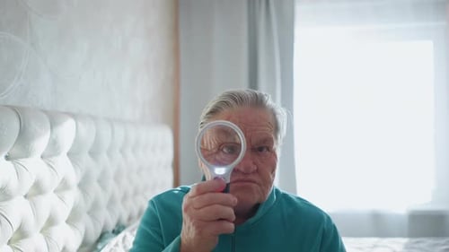Senior Woman Examining with Magnifying Glass Indoors