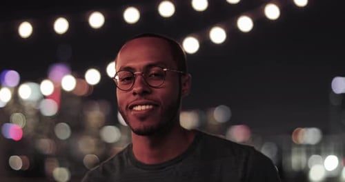 Smiling man with glasses at a rooftop party