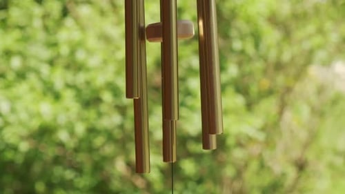 Metal wind chime natural green background slow motion 120p
