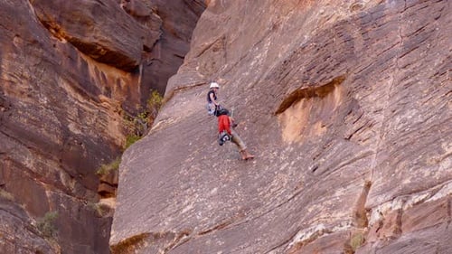 Un homme et une femme repoussent une énorme paroi rocheuse dans le parc national de Zion, dans l'Utah