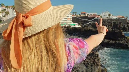 Woman in Hat Points to Beautiful Coastline