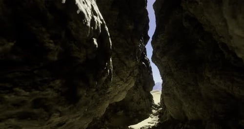 Narrow Canyon Reveals Distant Landscape Under Bright Blue Sky
