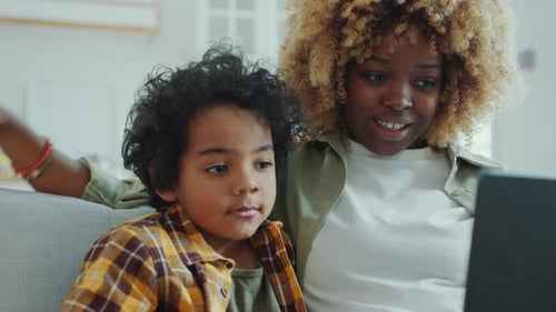 Cheerful Mother and Son Watching Cartoon on Laptop and Laughing at Home