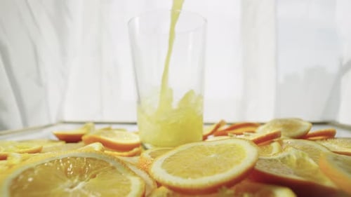 Pouring Fresh Orange Juice into Glass with Slices