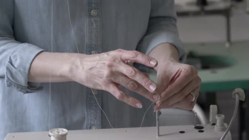 Woman threads sewing machine in fabric design studio in Canada slow motion
