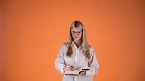 Thoughtful Young Blonde Woman Holding Pencil and Book, Colorful Studio Shot