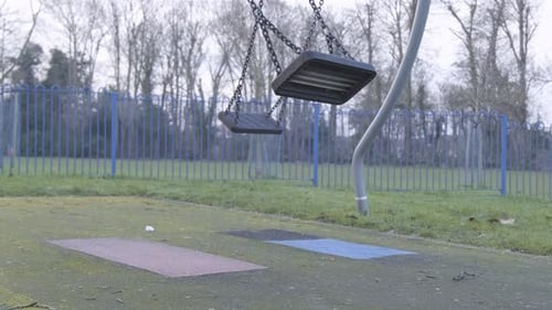 Balançoire vide sur une aire de jeux pour enfants sans personne par temps froid et nuageux dans le centre de Londres.
