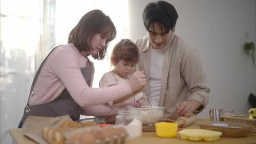 Family enjoys cooking time together in the kitchen with their child making cupcakes