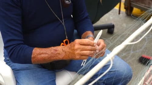 Alter Fischer repariert tagsüber Fischernetze.