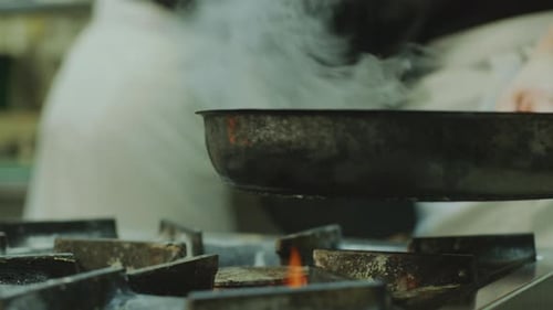 Chef Frying Food in Skillet on Gas Stove in Restaurant Kitchen