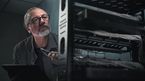 Man Inspecting Server Rack Using a Tablet