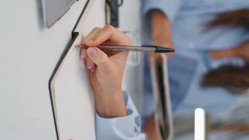 Woman Writing in Notepad at Desk in Office