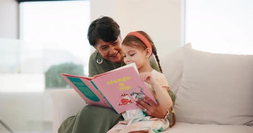 Woman Reads Book to Girl Indoors During Daytime