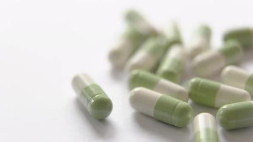 White and green capsules on a white lighted surface