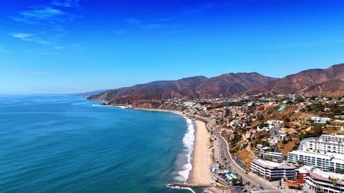 Sunny shore of the Pacific Ocean with mountain range.