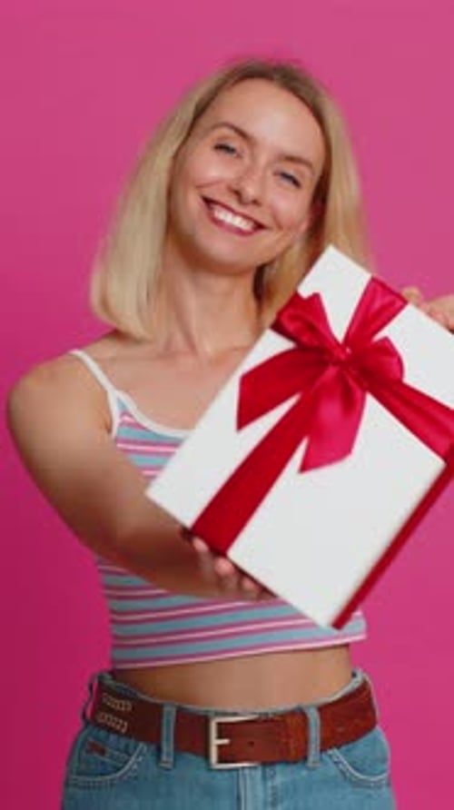 Smiling Woman Holds a Gift Box on Pink