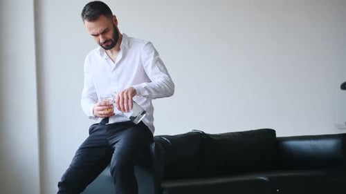 In formeller Kleidung. Geschäftlicher Misserfolg. Der verärgerte junge Trinker und Alkoholiker ist drinnen
.